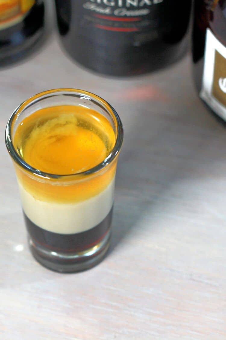 B52 cocktail on table with bottles of liqueur