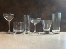 Several bar glasses lined up against dark background