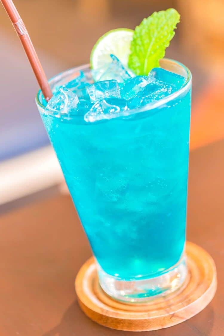 Blue Long Island Iced Tea drink with straw and mint and lime garnish