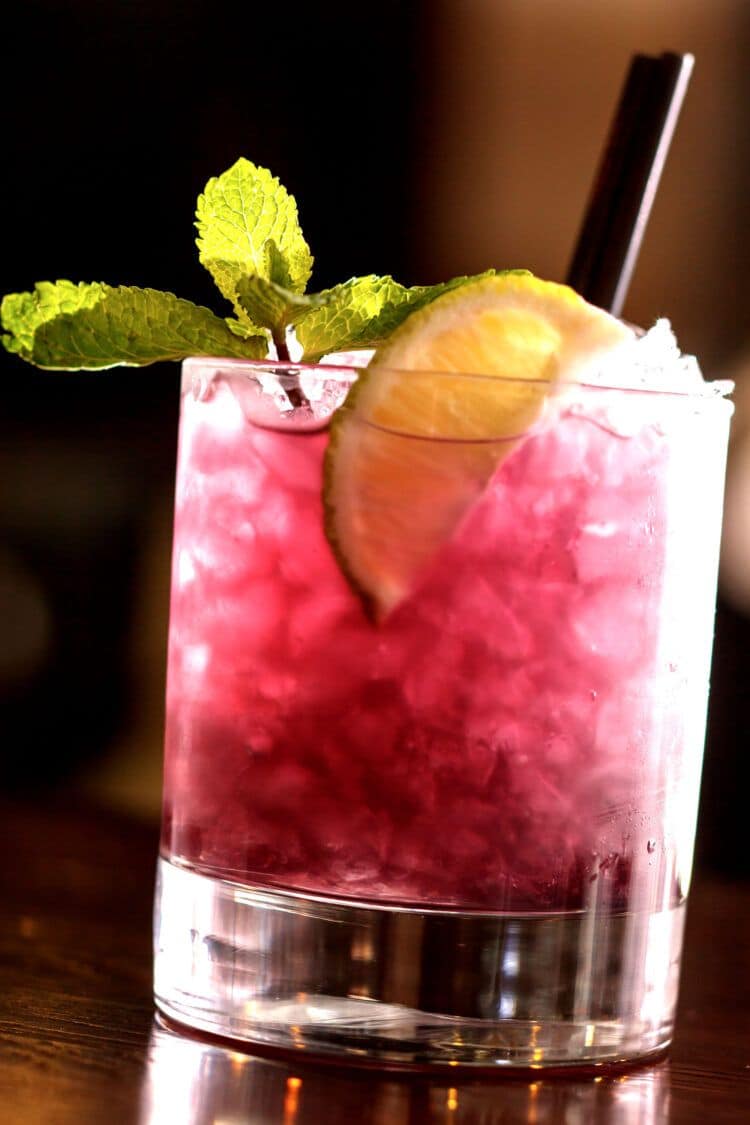 Blue Nectar Blackberry Bramble cocktail on bar with mint garnish