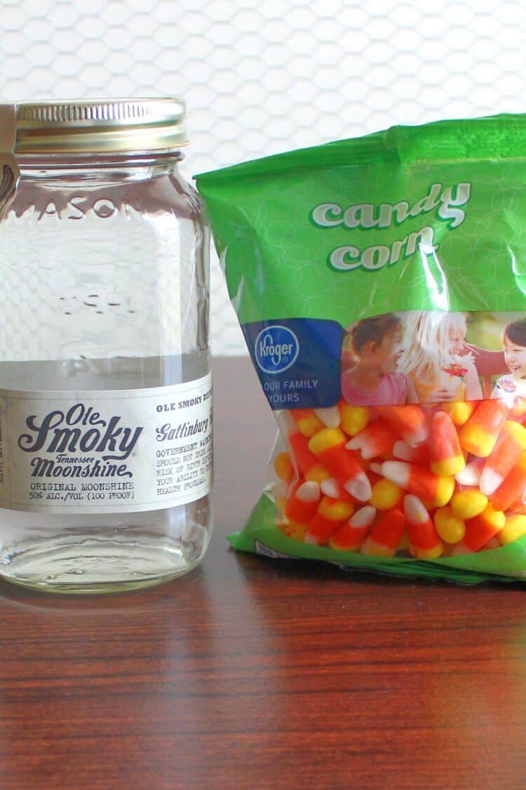 Bottle of moonshine next to bag of candy corn