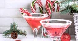 Two Christmas drinks garnished with candy canes and surrounded by Christmas decor