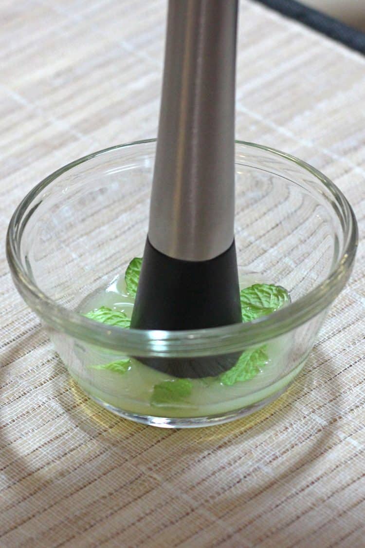 Cocktail Muddler crushing mint leaves in bowl