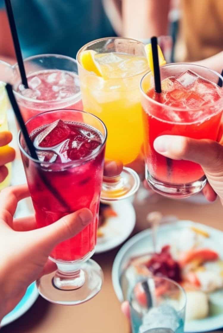 People clinking cocktail glasses together over table