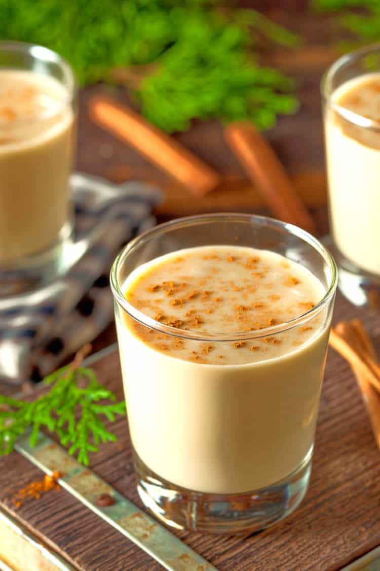 Glasses of eggnog on table with cinnamon sticks