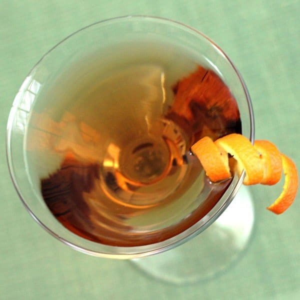 Overhead view of Fox River Cocktail with orange twist on light green background