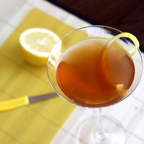 Overhead view of Hennessy Martini with lemon twist with lemons on cutting board