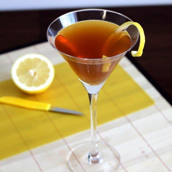 Hennessy Martini with lemon twist with lemons on cutting board