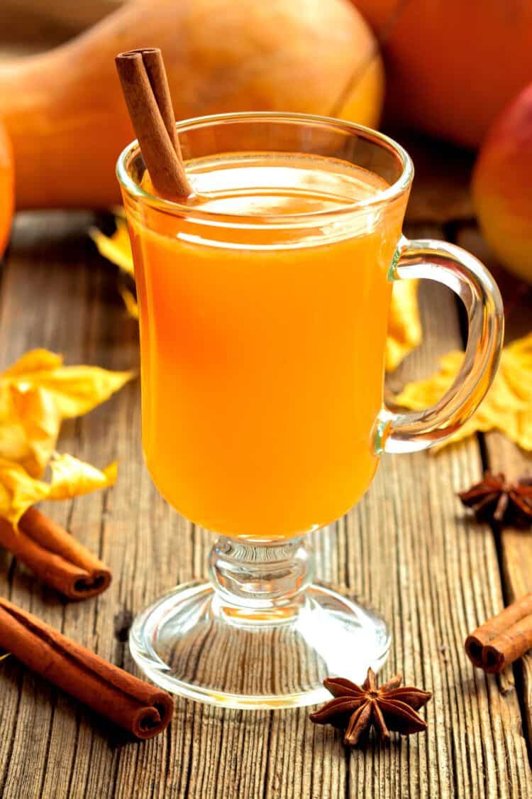 Hot Toddy cocktail on table with fall leaves and gourds