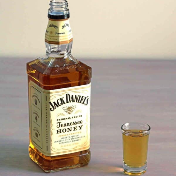 Bottle of Jack Daniels Tennessee Honey next to shot glass of same