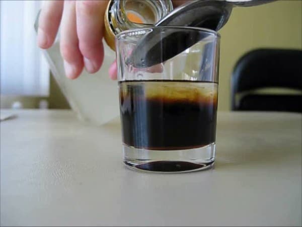 Pouring third layer of cocktail over back of spoon