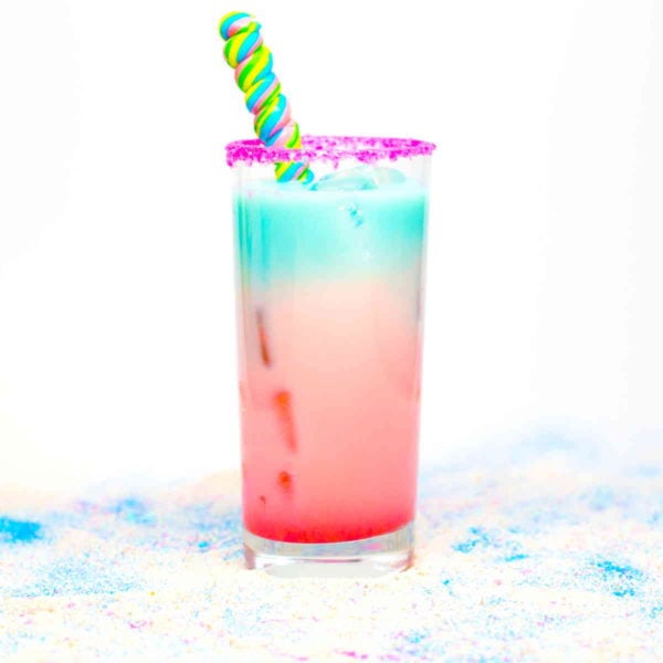 Red and blue layered Loco Unicorn cocktail on multi-colored sand