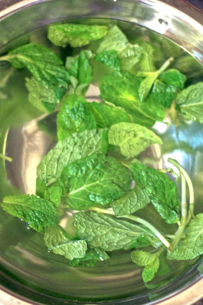 Mint leaves soaking in bowl of water