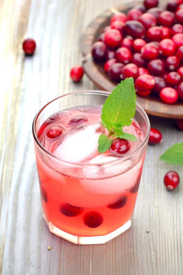 Pinkish Mistletoe Martini cocktail with cranberries and mint leaves