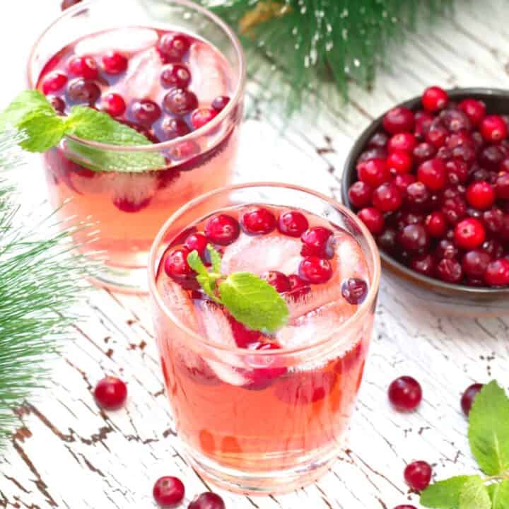 Pinkish Mistletoe Martinis cocktail with cranberries and mint leaves