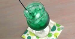 Tilted view of deep green Misty Mint cocktail in hurricane glass