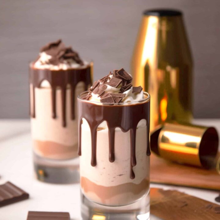 Two Mudslide cocktails in tall glasses with chocolate syrup and whipped cream