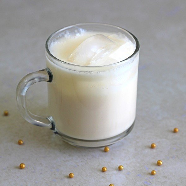 Nagel Nectar drink in glass mug with ice surrounded by gold pearls