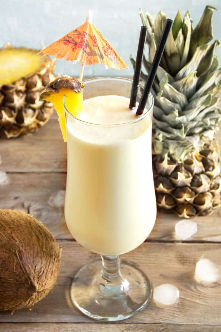 Overhead view of Pina Colada drink on table with pineapple and coconut