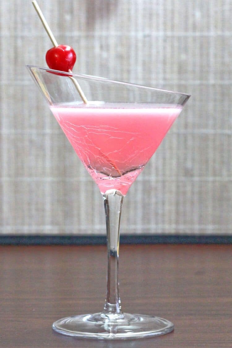 Pink Lady cocktail on table with cherry garnish