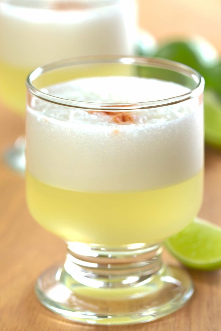 Pisco Sour cocktails on table with lime wedges