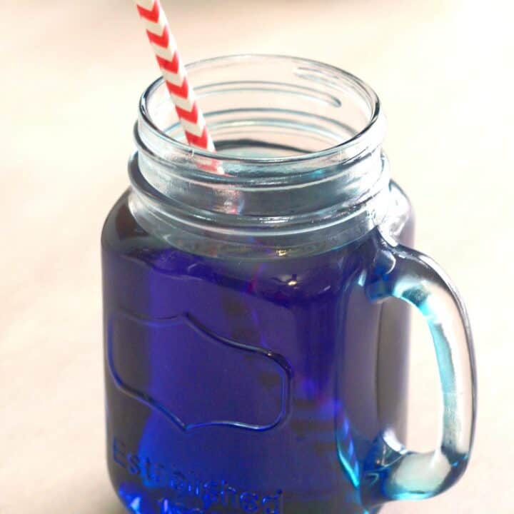 Prison Blues cocktail served in mason jar glass with paper straw