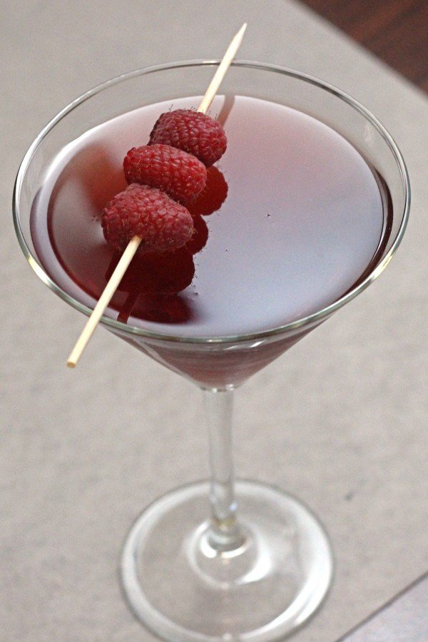 Raspberry Blush drink in cocktail glass with speared raspberries