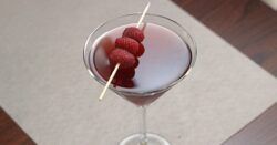 Raspberry Blush drink in cocktail glass with speared raspberries