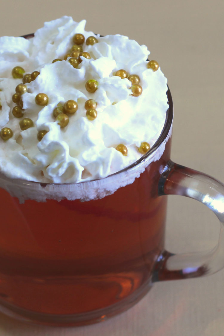 Tilted angle view of Red Rudolph cocktail with whipped cream and gold pearl sprinkles