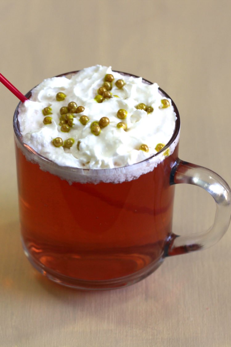 Red Rudolph cocktail with whipped cream and gold pearl sprinkles