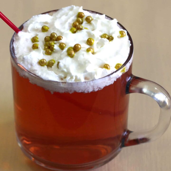 Red Rudolph cocktail with whipped cream and gold pearl sprinkles