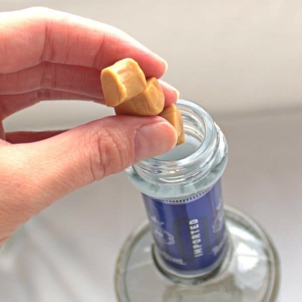 Putting chopped caramel candies into vodka bottle