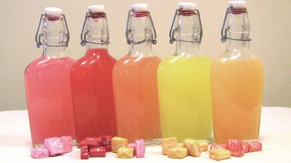 Finished Starburst Vodka infusions in their flasks with candies scattered around
