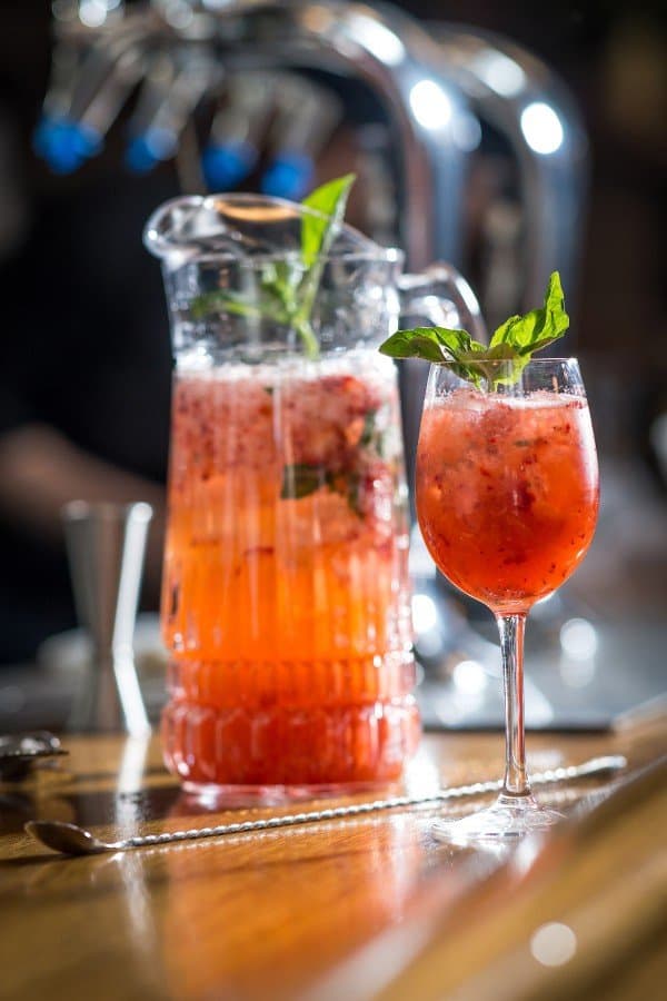 Strawberr Smash drink in glass next to pitcher of same