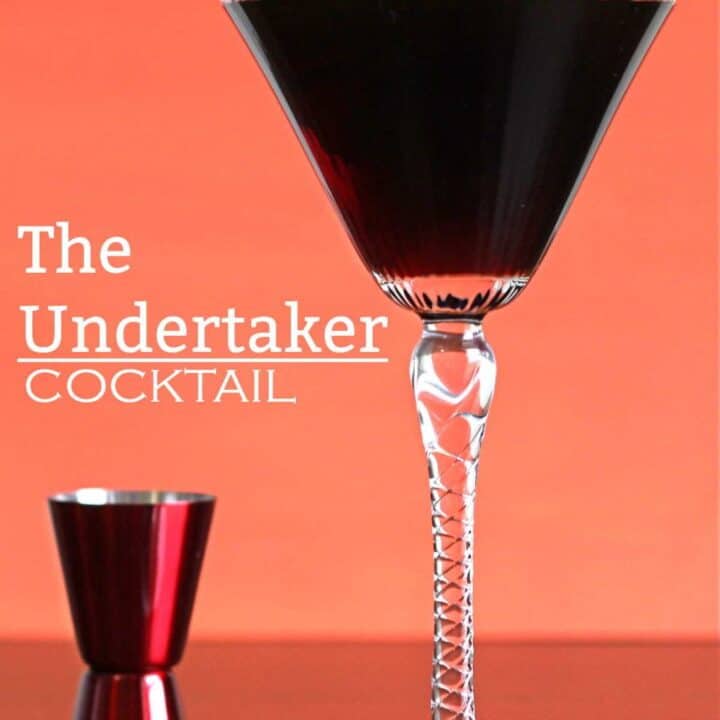 Dark brown Undertaker cocktail in tall martini glass next to red jigger