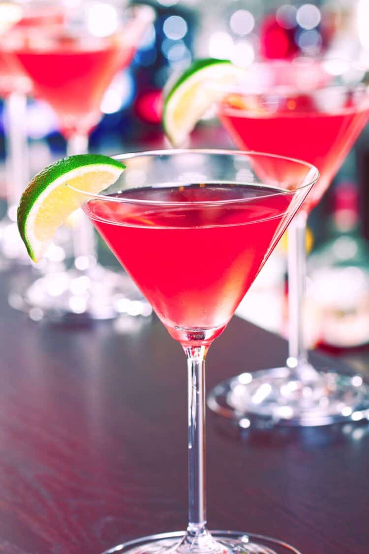 Three Vodka Cranberry drinks in cocktail glasses on a bar