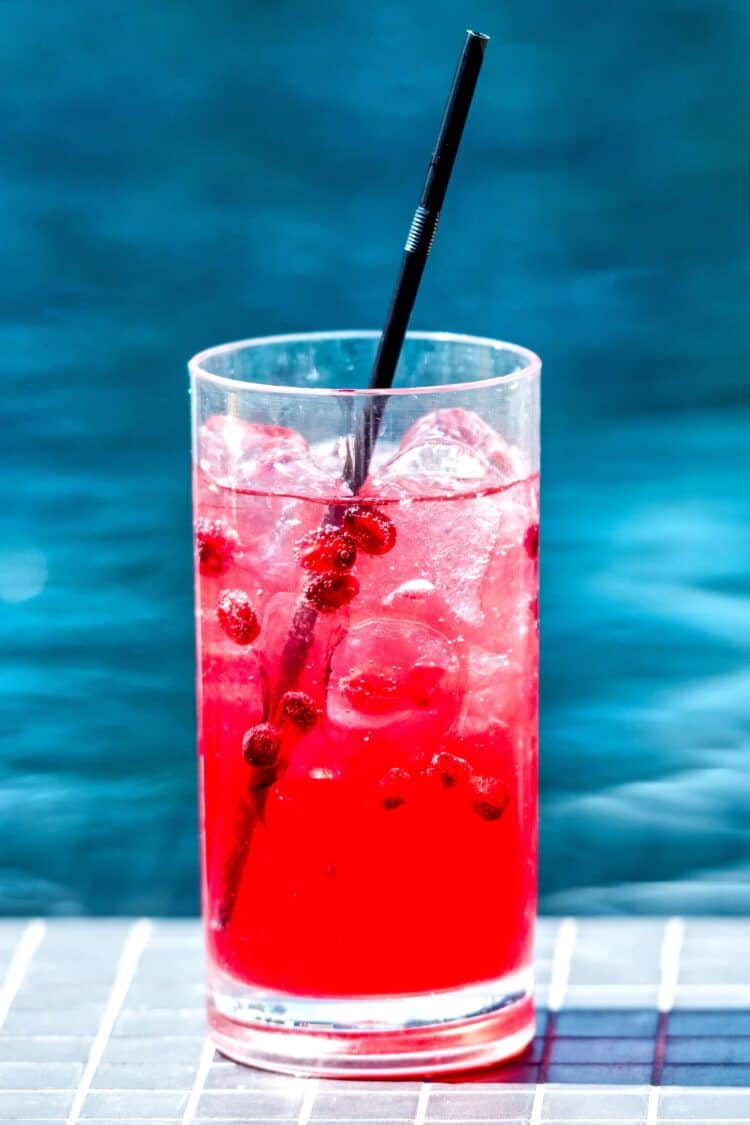 Vodka Cranberry Drink in tall glass with cranberries by poolside