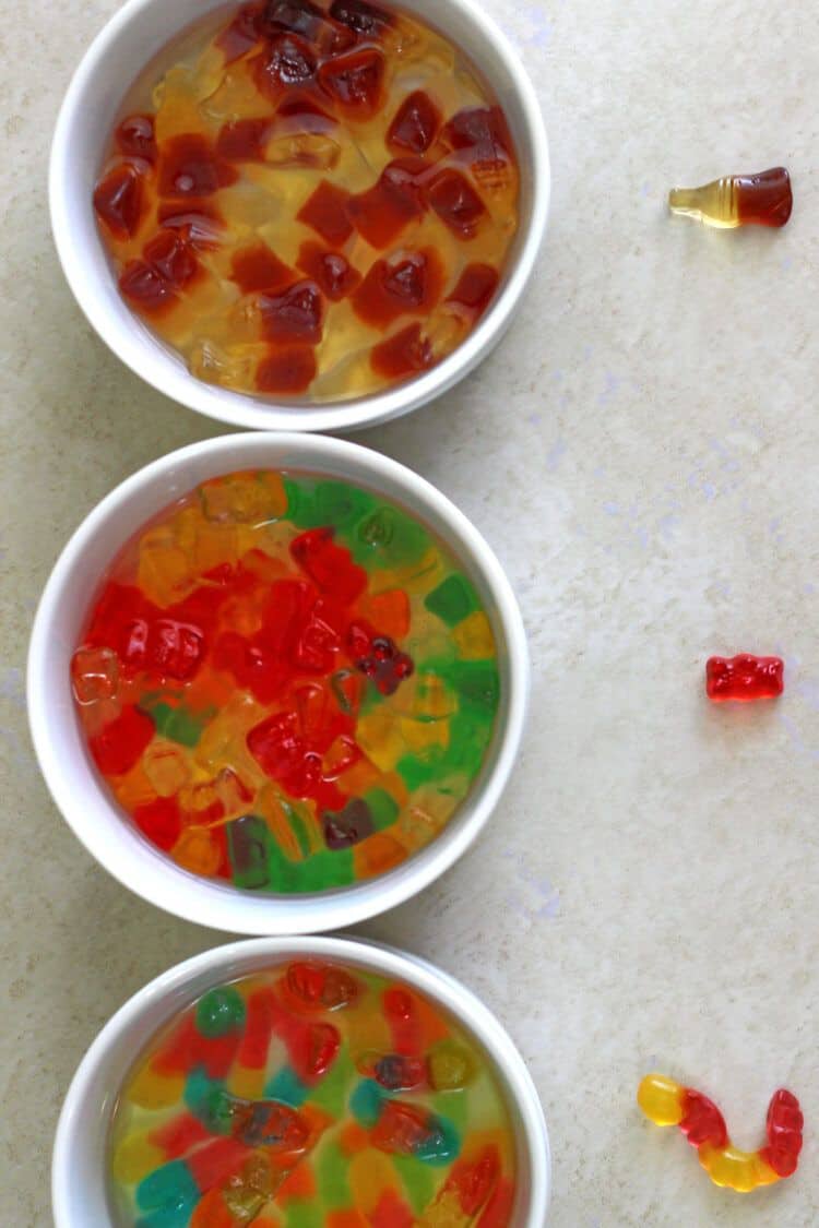 Gummy bears, worms and colas soaking in vodka in white bowls